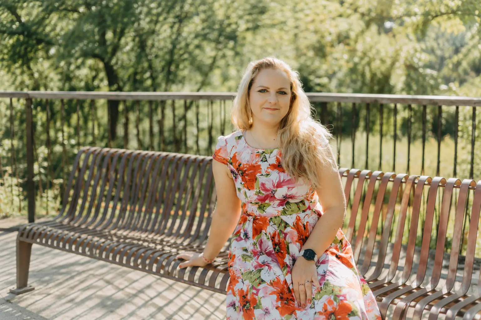 Décoratrice Bouches-du-Rhône, portrait de Jennifer, souriante avec une robe blanche à fleurs assis sur un banc