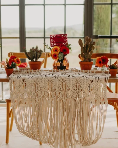 décoration mariage thème folk, de belles fleurs rouges et orange sur une table avec une nappe tissée