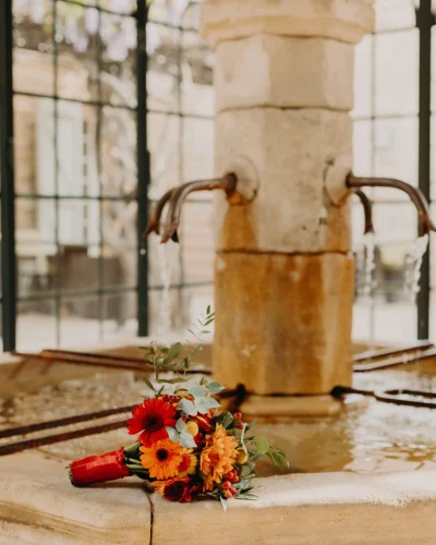 photo d'une fontaine ancienne avec des fleurs rouges et oranges